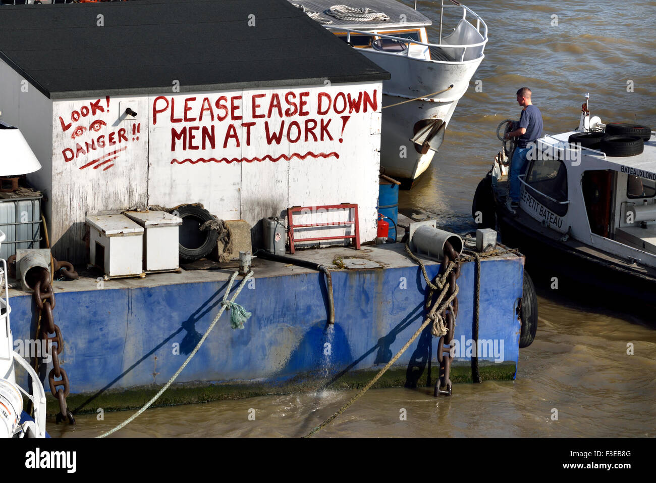 Londra, Inghilterra, Regno Unito. Avviso su una chiatta nel fiume Tamigi - Si prega di facilità verso il basso - uomini al lavoro Foto Stock