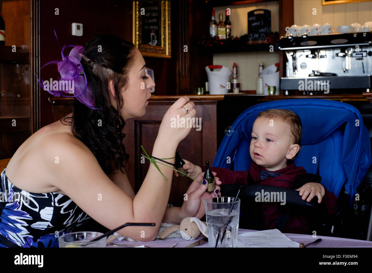 Giovane madre soffiare bolle per il suo bambino a un ricevimento di nozze Inghilterra Regno Unito Foto Stock