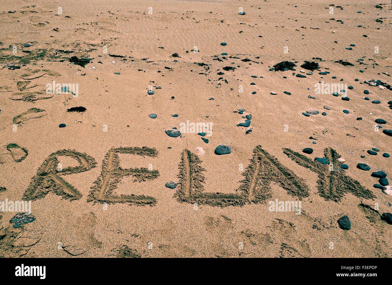 Vacanze a sfondo con relax parola scritta sulla spiaggia sabbiosa. Vacanze a sfondo. L'estate. In relax umore Foto Stock