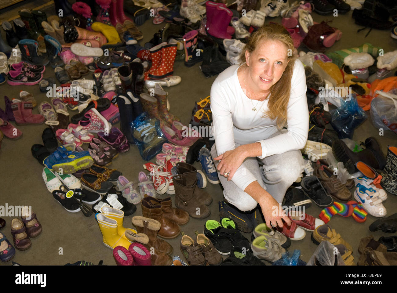 Co-fondatore di un appello per donazioni in denaro per aiutare i profughi fuggono lacerato dalla guerra Siria circondato da alcune delle calzature donati per... Foto Stock