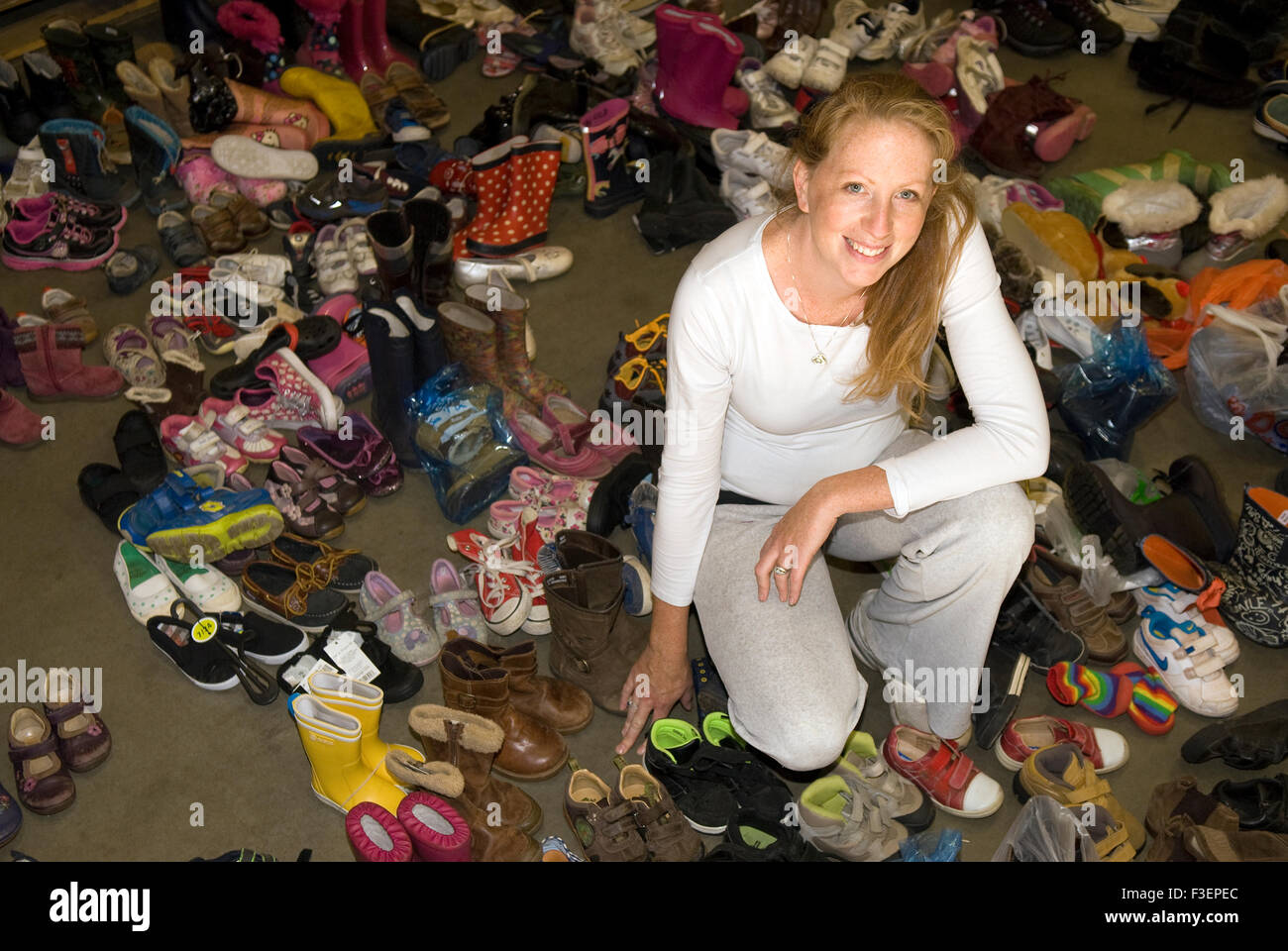 Co-fondatore di un appello per donazioni in denaro per aiutare i profughi fuggono lacerato dalla guerra Siria circondato da alcune delle calzature donati per shi Foto Stock