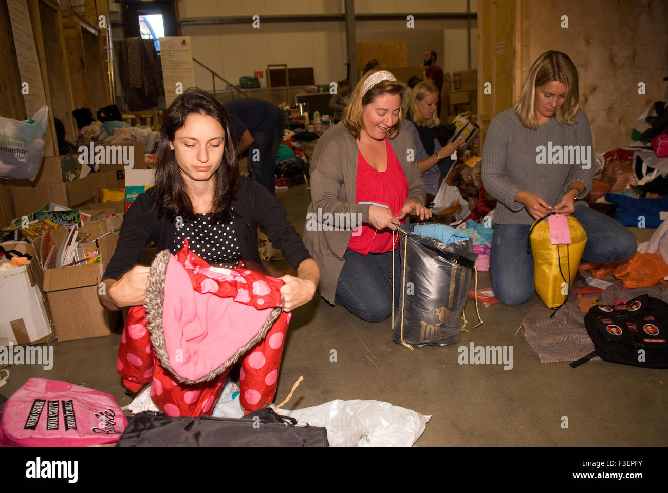 Volontari nel magazzino della compagnia di spedizione imballare gli articoli donati di abbigliamento e altri articoli per la spedizione in Grecia per aiutare i rifugiati siriani... Foto Stock