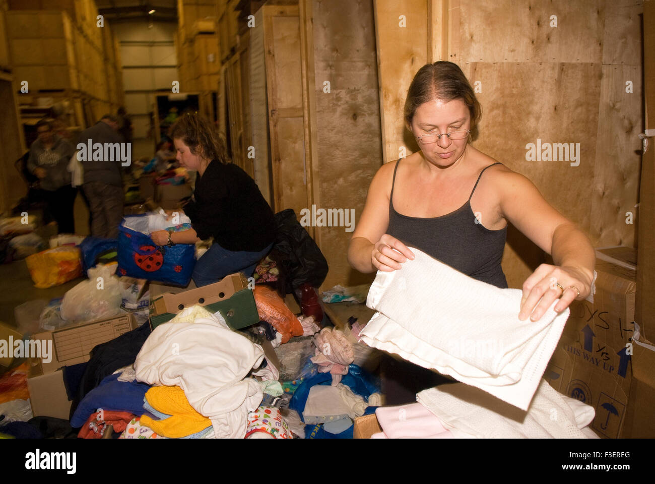 Volontario in una società di rimozione dal magazzino di imballare donati capi di abbigliamento e altri non deperibili per la spedizione a G Foto Stock
