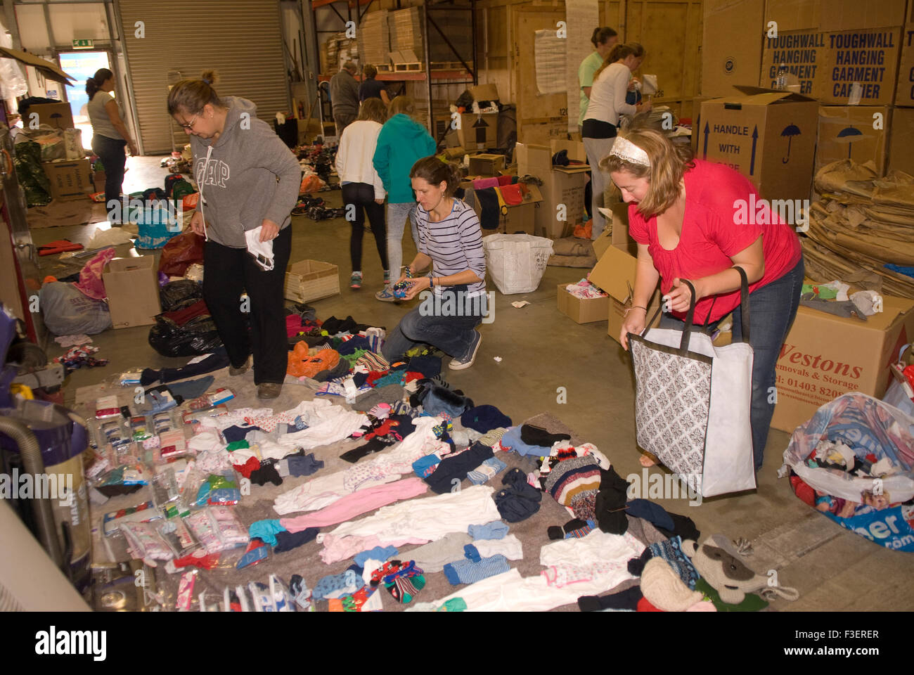 Volontari in un magazzino di un'azienda di traslochi smistamento e imballaggio su articoli donati di abbigliamento e altri articoli non deperibili per... Foto Stock