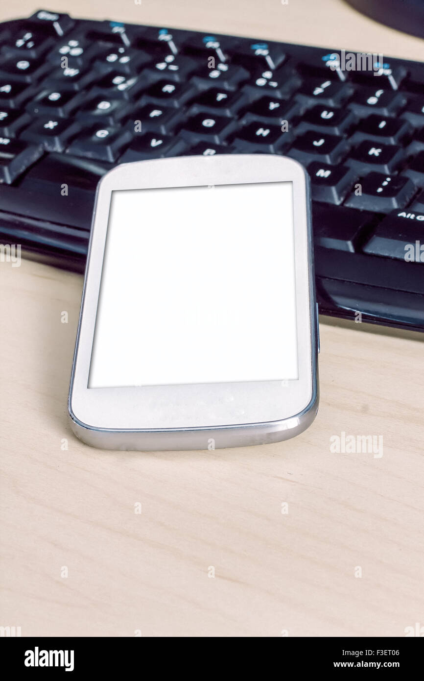 La visualizzazione di una schermata vuota di smartphone sul computer tastiera, il fuoco selettivo Foto Stock
