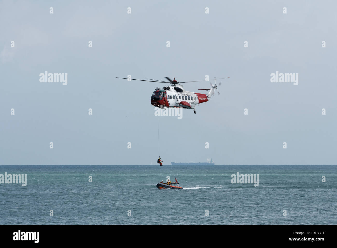 H.M Coastguard salvataggio elicottero abbassamento winchman a RNLI linshore scialuppa di salvataggio, lavorando insieme per l'esercizio al largo dell'isola di wight Coast, regno unito Foto Stock