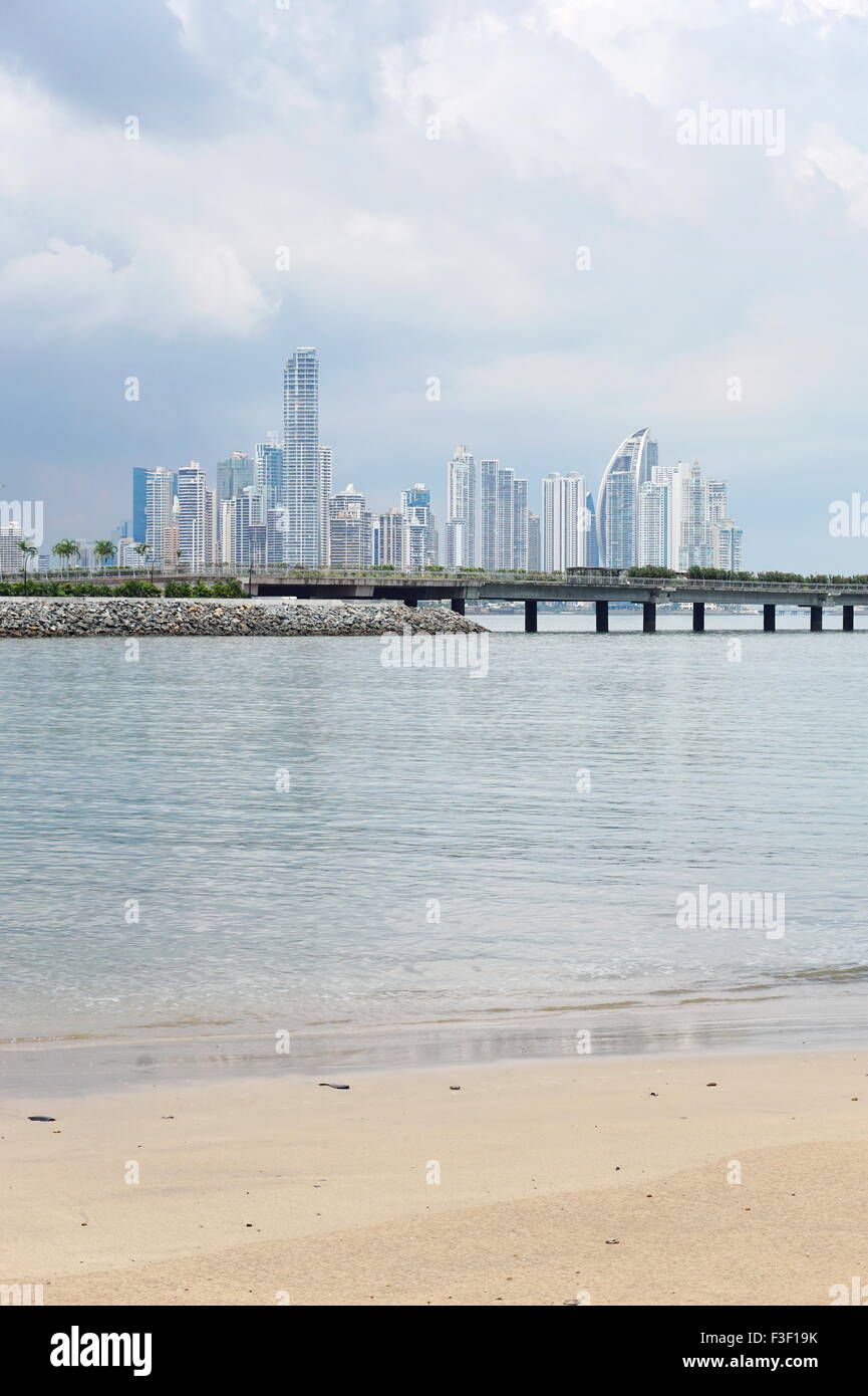 Spiaggia di sabbia con la nuova autostrada sulla baia e grattacieli del centro business della città di Panama in background, Panama Foto Stock