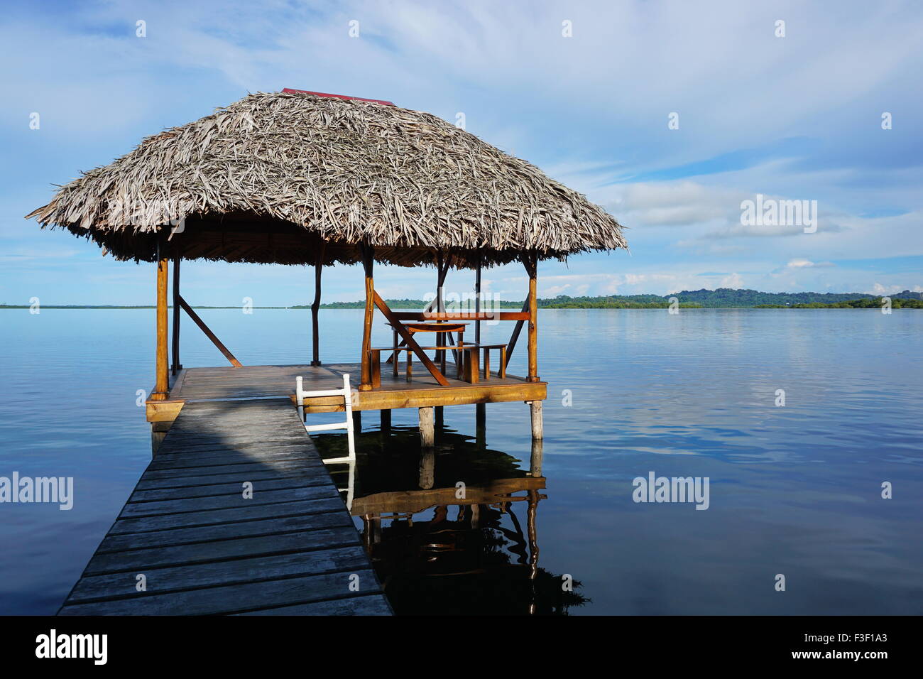 Capanna Palapa sopra l'acqua con palm con tetto in paglia tetto in una calma laguna Mar dei Caraibi, America centrale e di Panama Foto Stock
