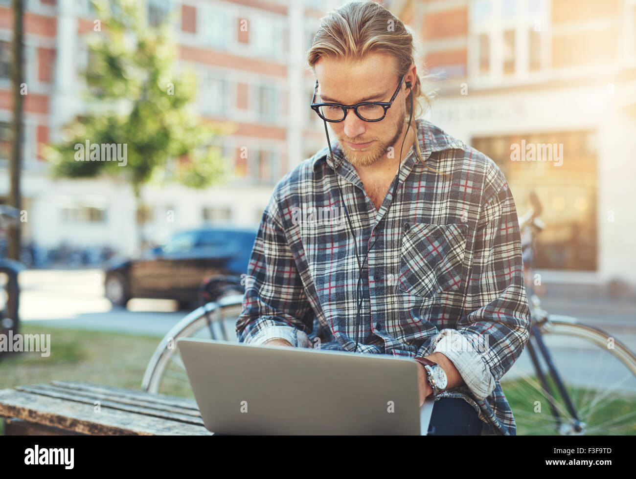 Concentrato giovane con il suo computer portatile, seduto fuori a lavorare Foto Stock
