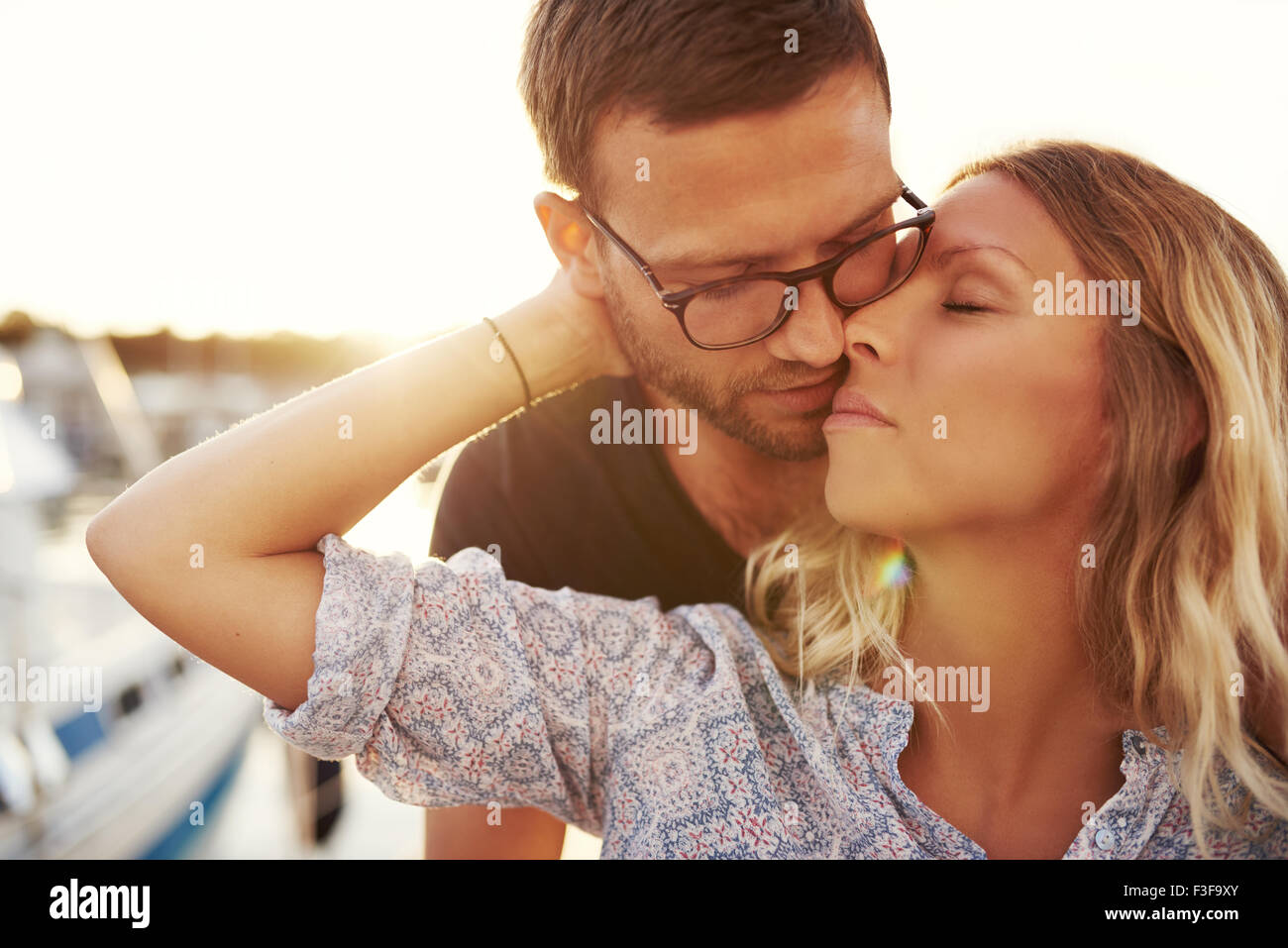 Paio di baciare in una serata estiva, Donna bionda e Uomo con occhiali Foto Stock