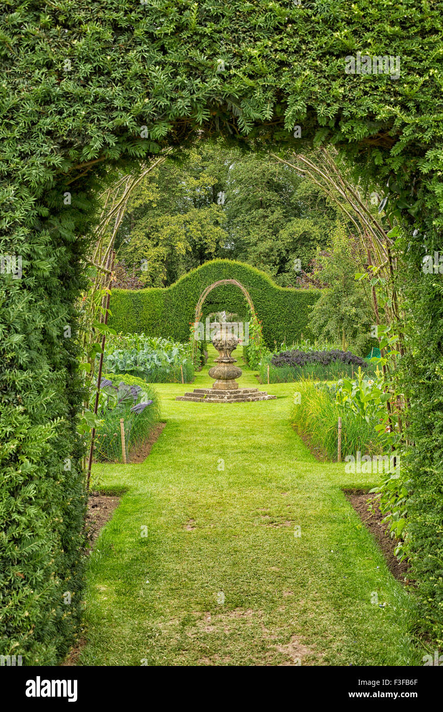 Bellissimo giardino inglese visto attraverso un cancello con pianta rampicante Foto Stock