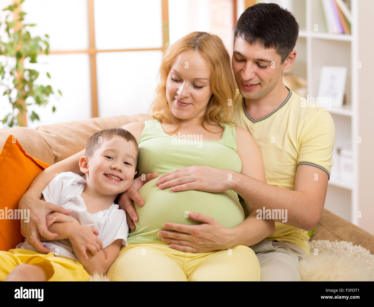 Famiglia aspettano di nuovo bambino. Little Boy e il padre suo abbraccio madre in stato di gravidanza Foto Stock