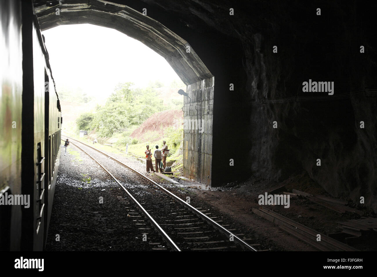 Treno che passa attraverso il tunnel i lavoratori del settore ferroviario permanente sulla apertura del tunnel ferroviario Konkan route ; Maharashtra ; India n. MR Foto Stock