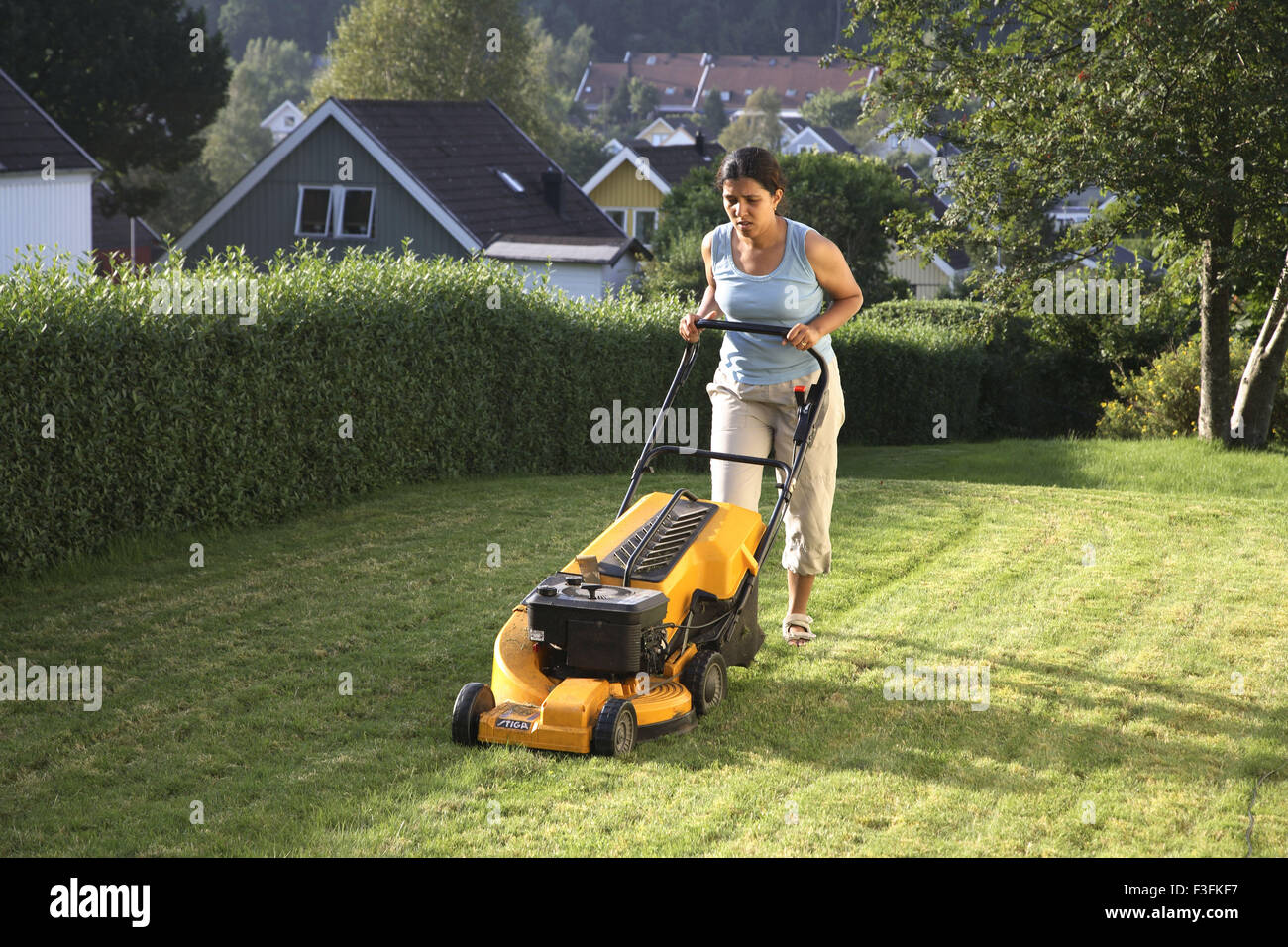 Giovane donna cresciuto di taglio erba di prato dalla macchina di taglio ; Skepllanda ; Svezia signor#468 Foto Stock