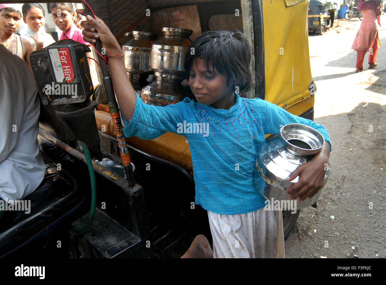 Una giovane ragazza riempire di acqua potabile in contenitori di acciaio inossidabile in un rickshaw in corrispondenza di una delle baraccopoli in Chembur ; Bombay ora Mumbai Foto Stock