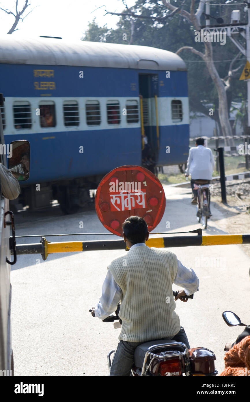 Attraversando il binario ferroviario che mostra la scheda di arresto ; India Foto Stock