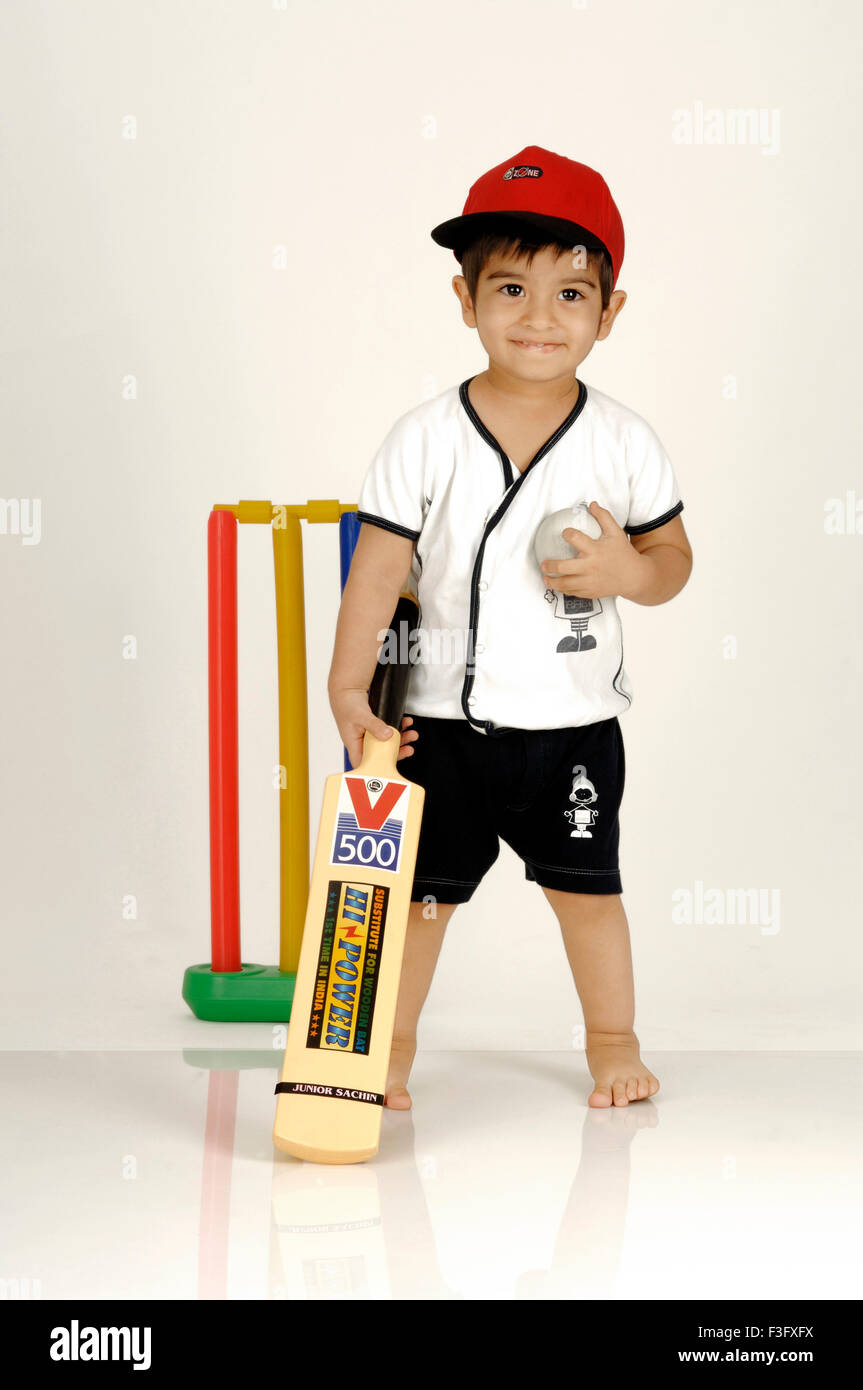 Ragazzo indiano con Bat & Ball pronto per giocare a cricket ; fiero battitore ; MR Foto Stock