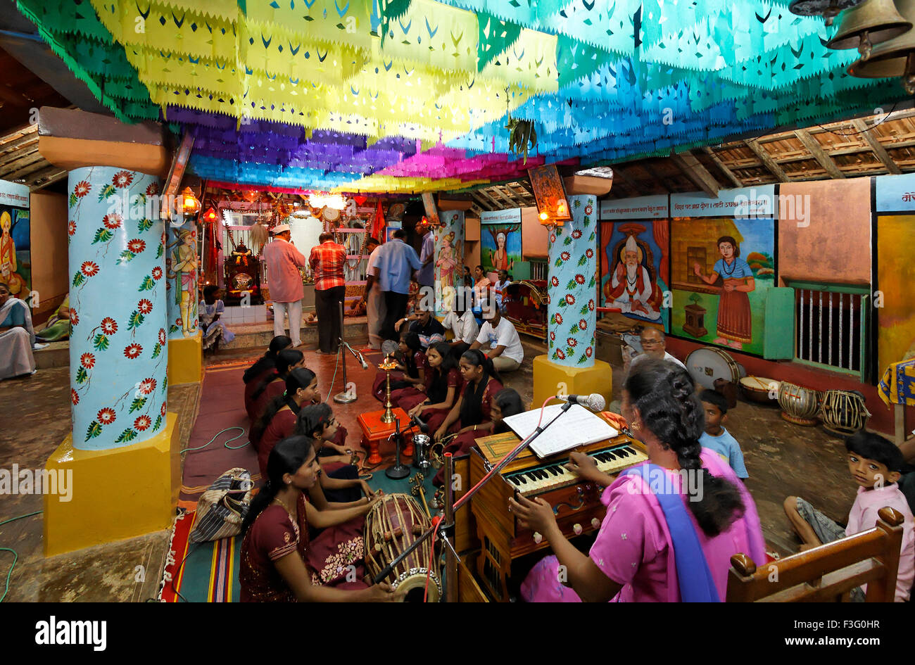 Ragazze che cantano bhajan suonando strumenti musicali harmonium tabla nel tempio ; India ; asia Foto Stock