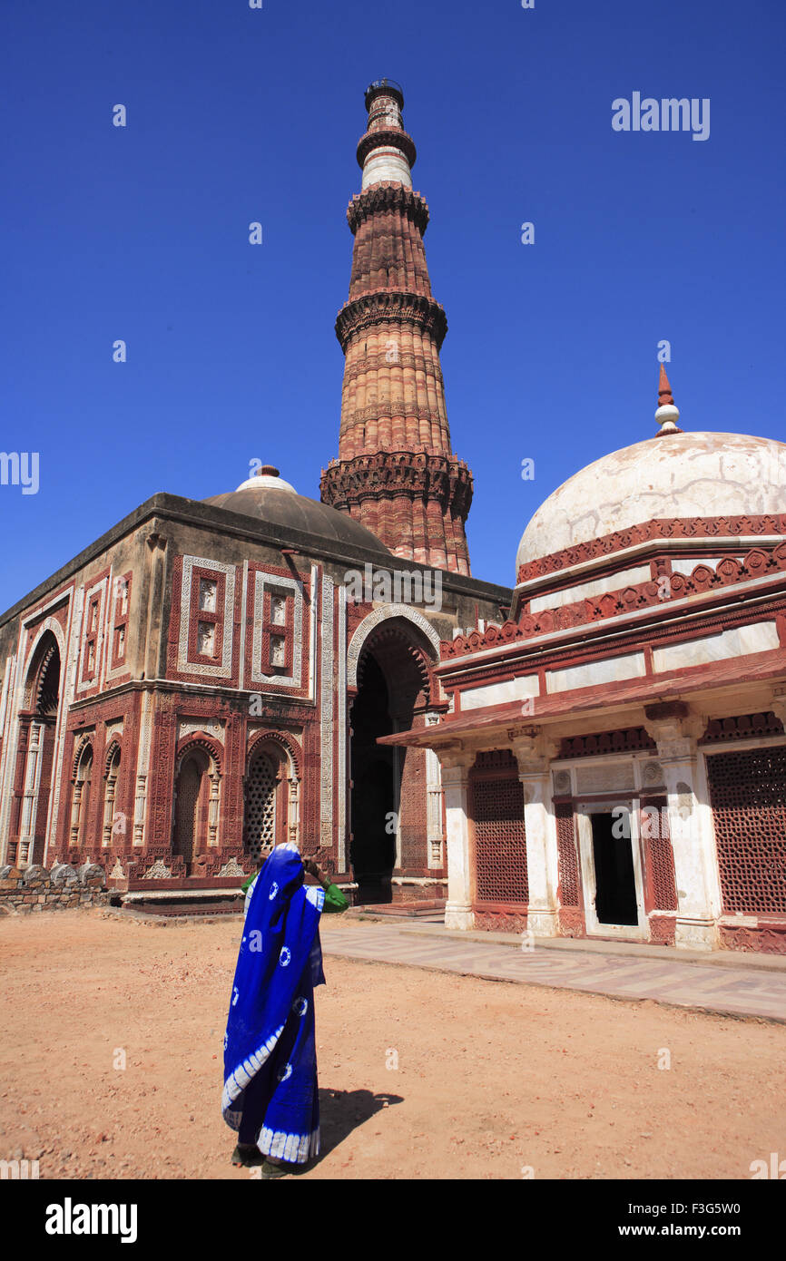 Donna guardando Alai Darwaza Imam Zamin la tomba e Qutab Minar costruito nel 1311 pietra arenaria rossa torre ; Indo arte musulmana ; Delhi Foto Stock