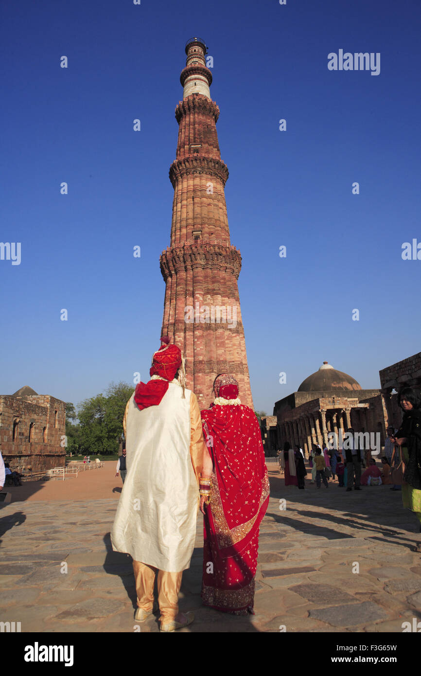 American sposi in costume indiano di fronte Qutb Minar pietra arenaria rossa torre Indo arte musulmana Delhi Foto Stock