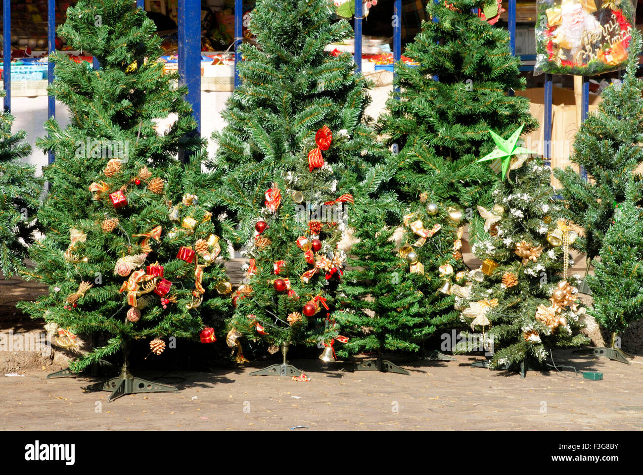 Decorate artificiale alberi di Natale tenuto per vendere nella parte anteriore del negozio a Borivali ; Bombay ora Mumbai ; Maharashtra ; India Foto Stock