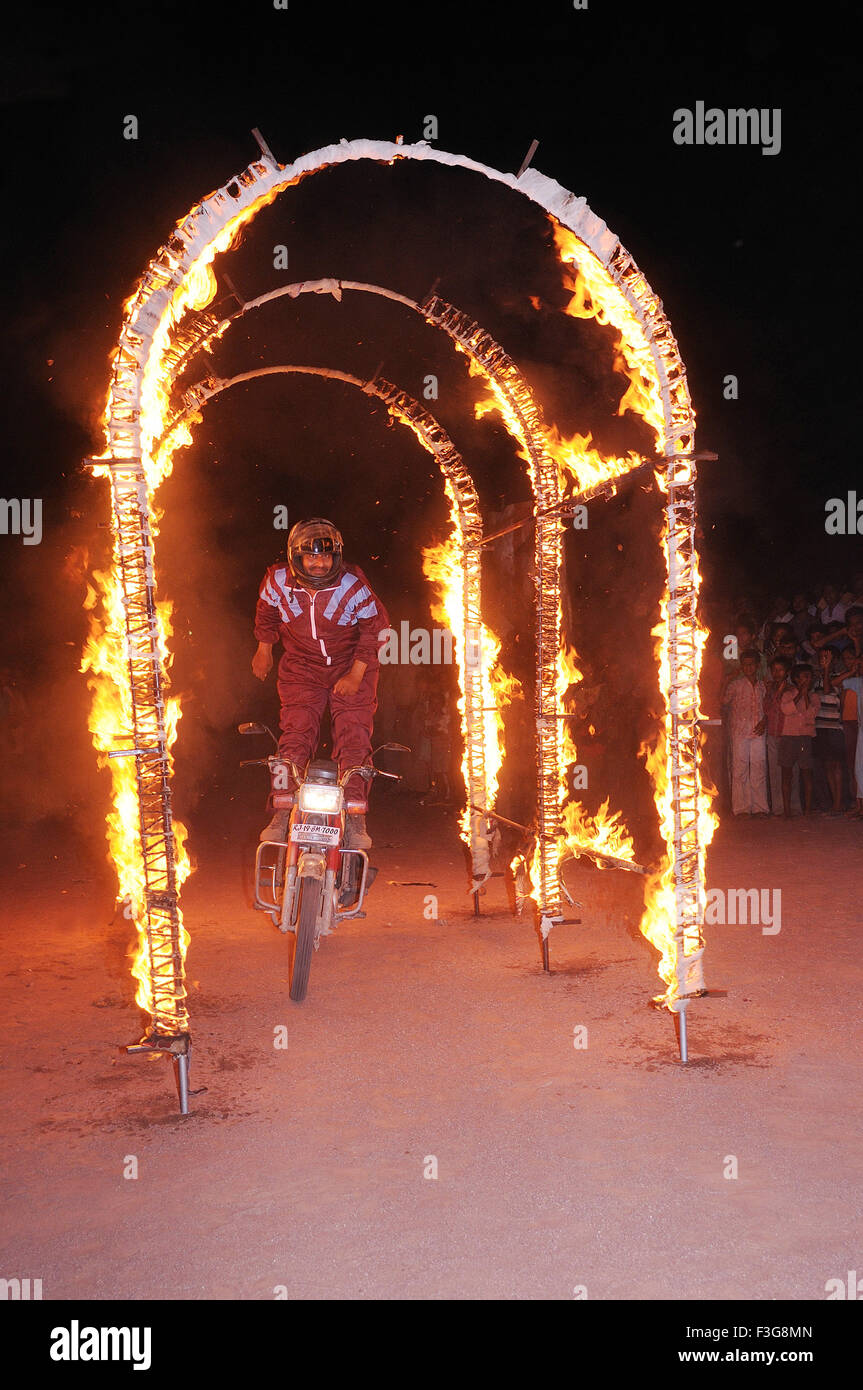 Uomo in piedi sulla bici del motore di guida attraverso il fuoco arch ; Jodhpur ; Rajasthan ; India Foto Stock