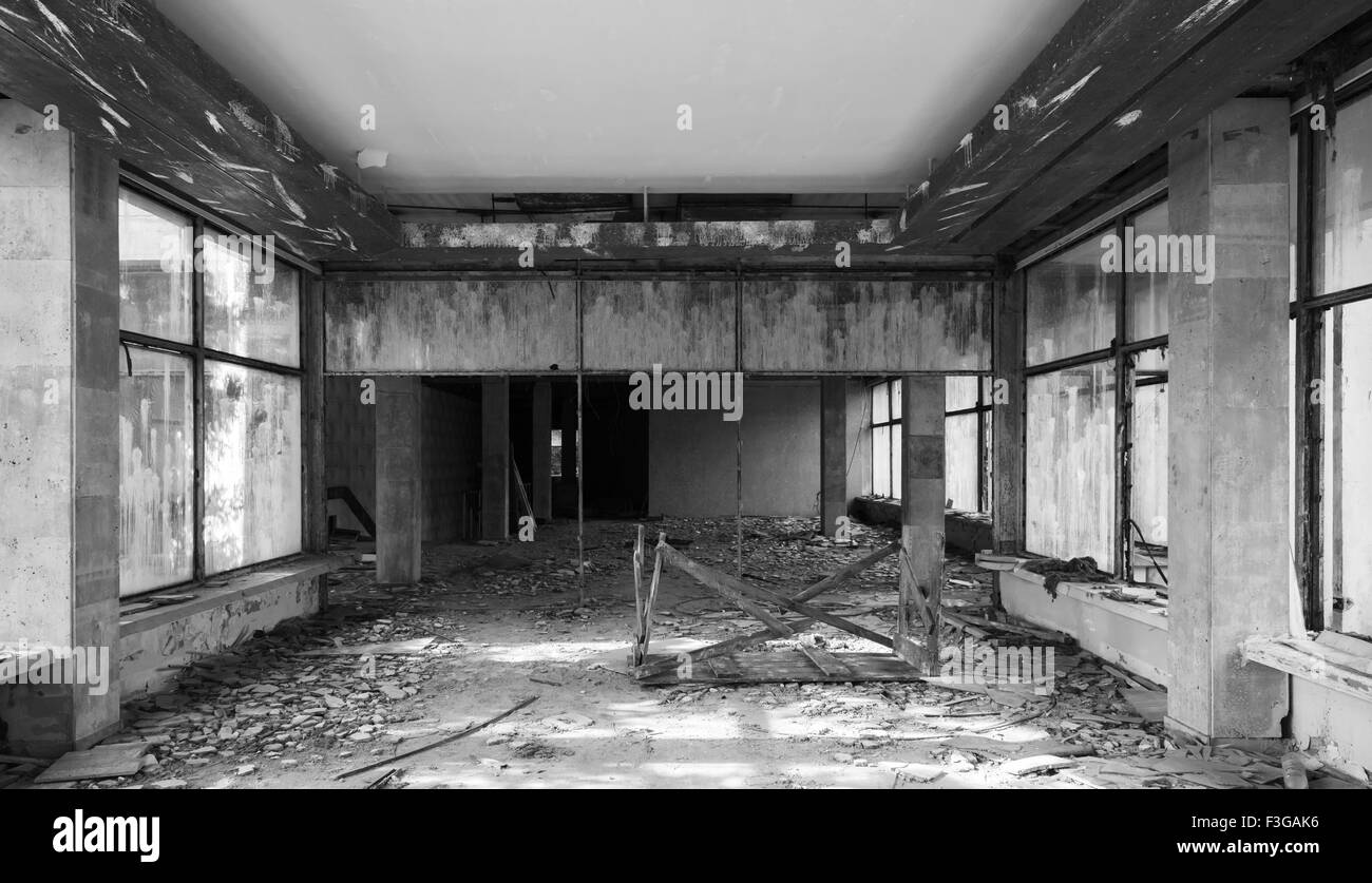Edificio abbandonato interni. Hall prospettiva con sporcizia sul pavimento e il risarcimento danni, foto in bianco e nero Foto Stock