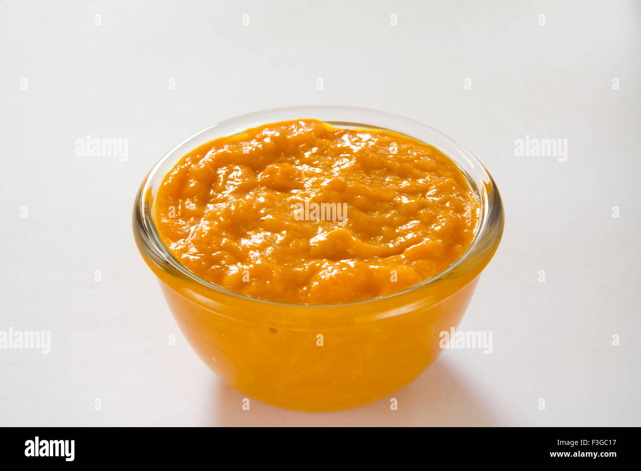 Aamras dolce piatto, pasta di frutta mango dessert servito in recipiente di vetro su sfondo bianco Foto Stock