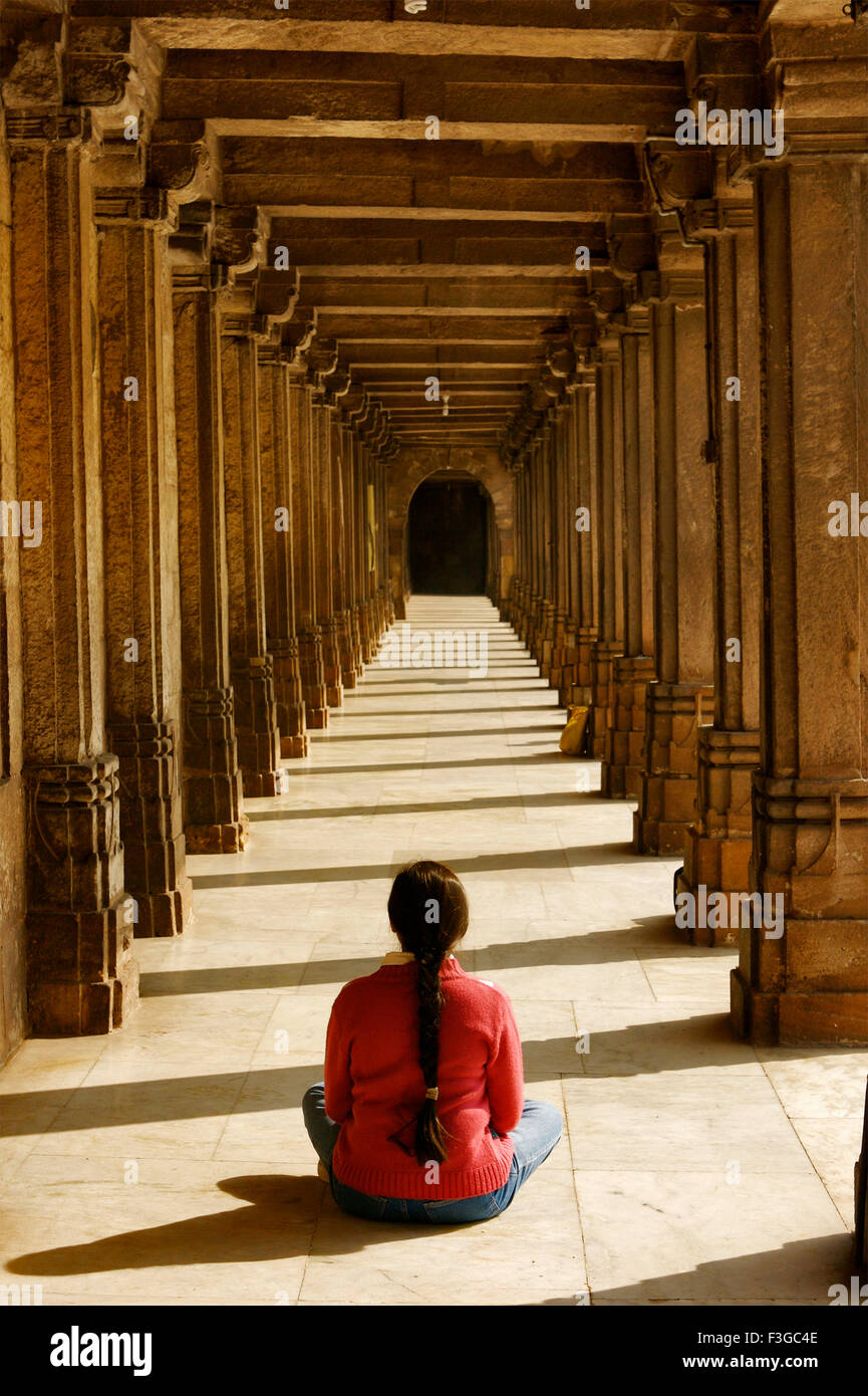 Donna in felpa rossa seduti in meditazione pongono nel passaggio di masjid Jumma ; Ahmedabad ; Gujarat ; India Foto Stock