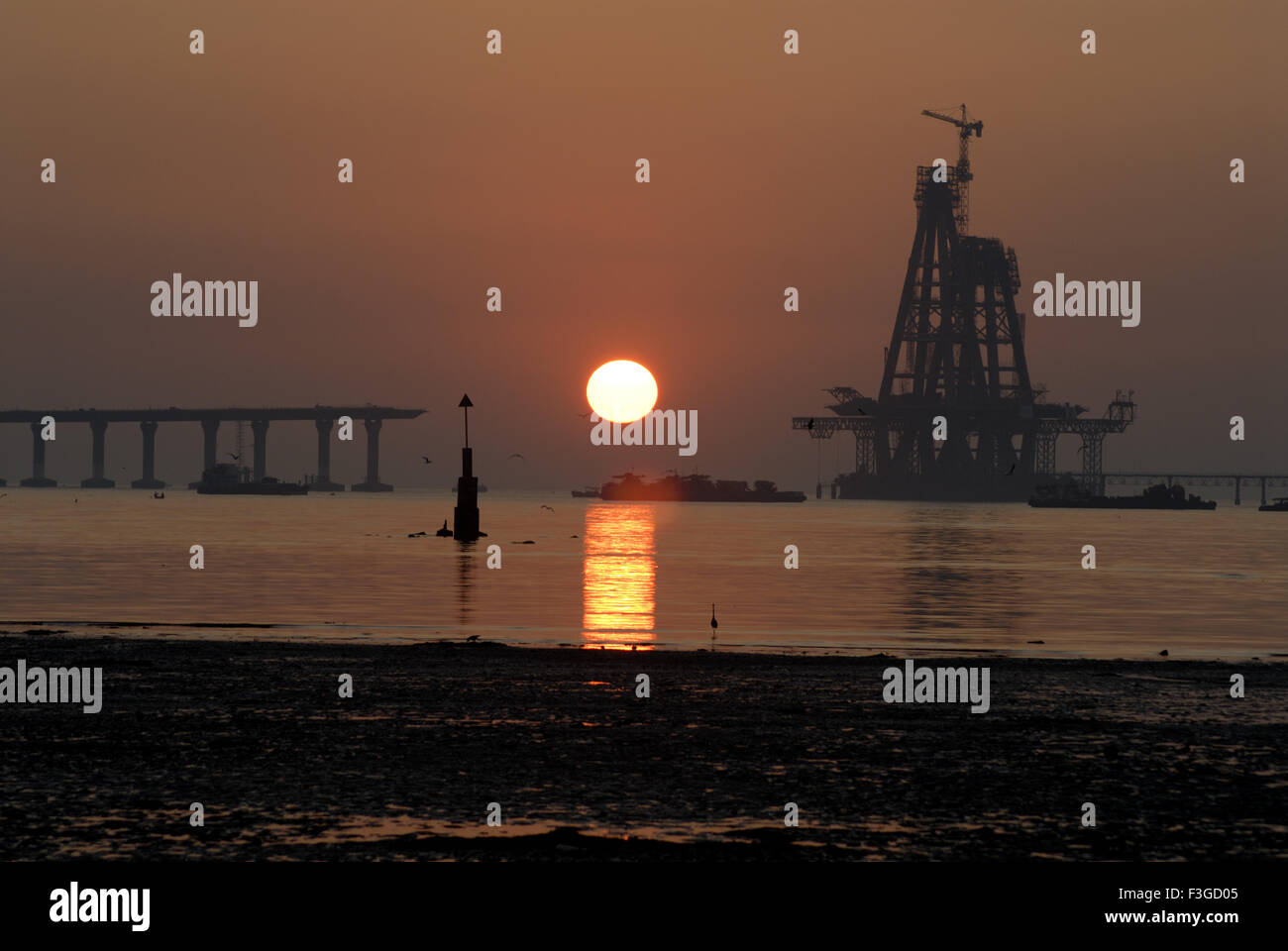 Tramonto a Mahim spiaggia vicino Worli mare ponte di collegamento in costruzione ; Mumbai Bombay ; Maharashtra ; India Foto Stock
