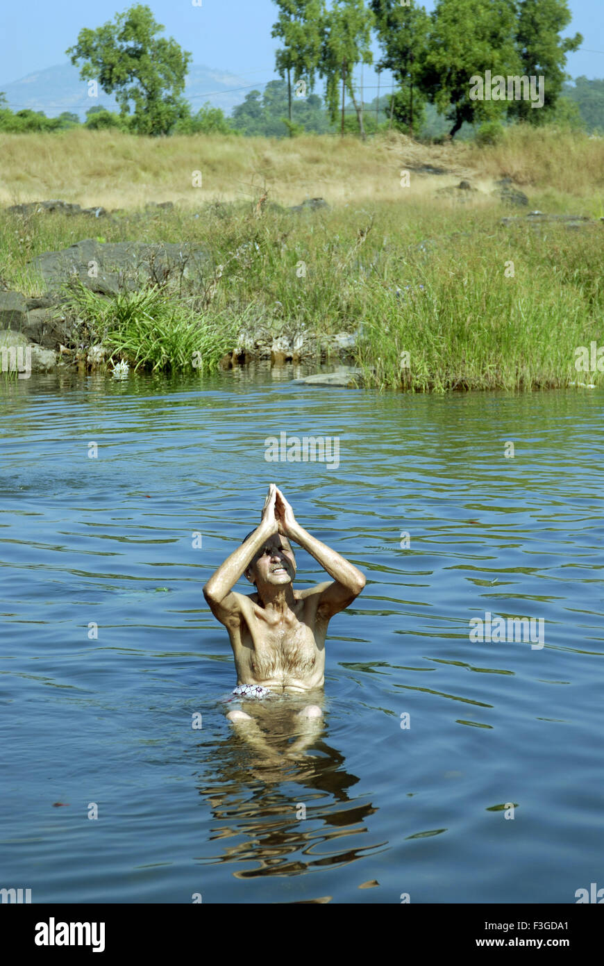 Uomo vecchio 80 anni adorare sun in seduta fiume Tansa a Vajreshwari Thane district ; Maharashtra ; India ; Asia MR Foto Stock
