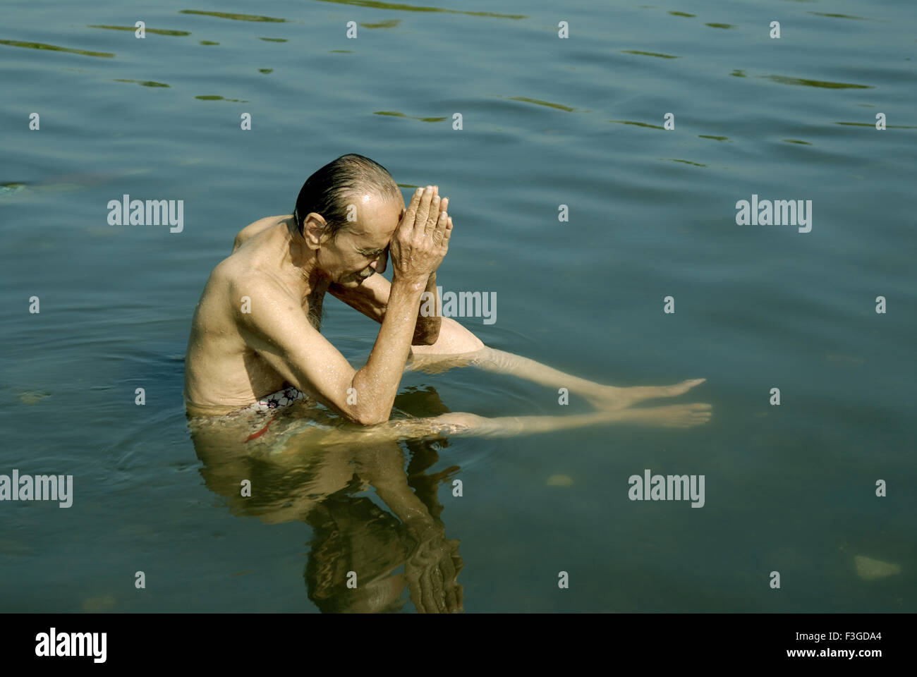 Il vecchio uomo che prega di Sun in seduta fiume Tansa a Vajreshwari Thane district Maharashtra India Asia MR Foto Stock