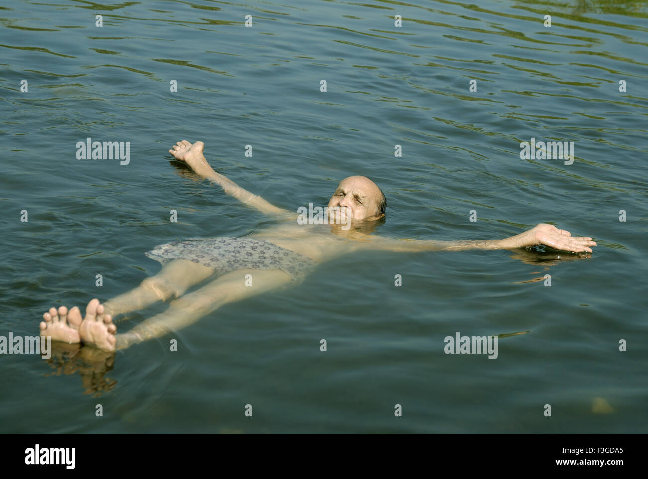 Il vecchio uomo nuoto galleggiante nel fiume Tansa a Vajreshwari Thane district ; Maharashtra ; India ; Asia MR Foto Stock
