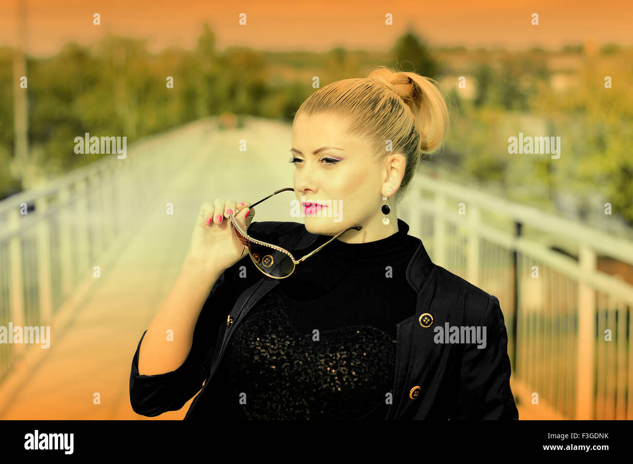 Ritratto di donna bella sul ponte ferroviario, una scena oltre la ferrovia, l'immagine in un tasto giallo, un soggetto fashionab Foto Stock