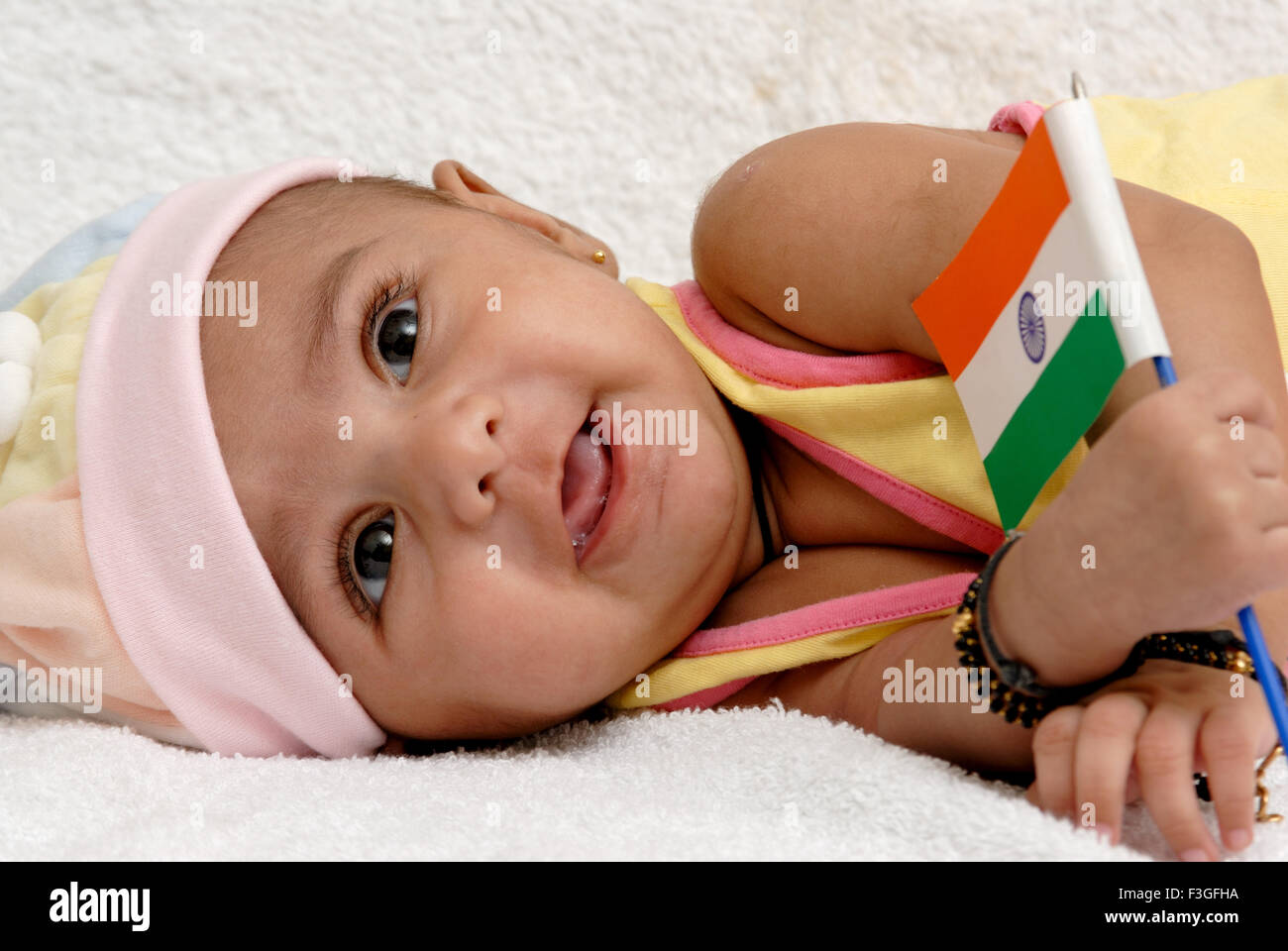 Indian baby Bambino giacente sul lato holding bandiera dell India in mano su sfondo bianco - signor#512 - 123488 rmm Foto Stock