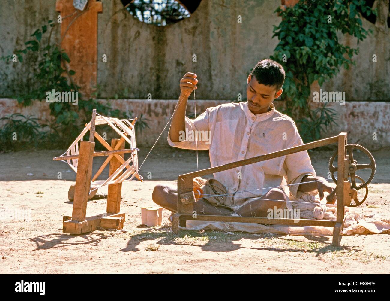 Un giovane ragazzo la filatura dei filati di cotone a un istituto basato su Gandhi pensieri di tessitura di filatura i propri vestiti Gujarat Foto Stock