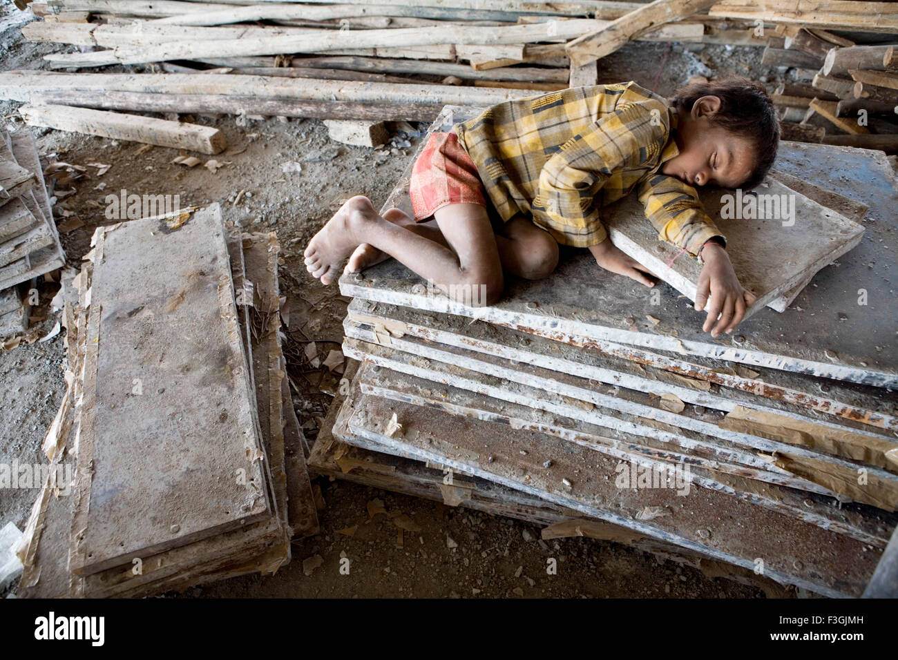 Giovane ragazzo dormire in mezzo a tutti i materiali di costruzione ; Ahmedabad ; Gujarat ; India Foto Stock