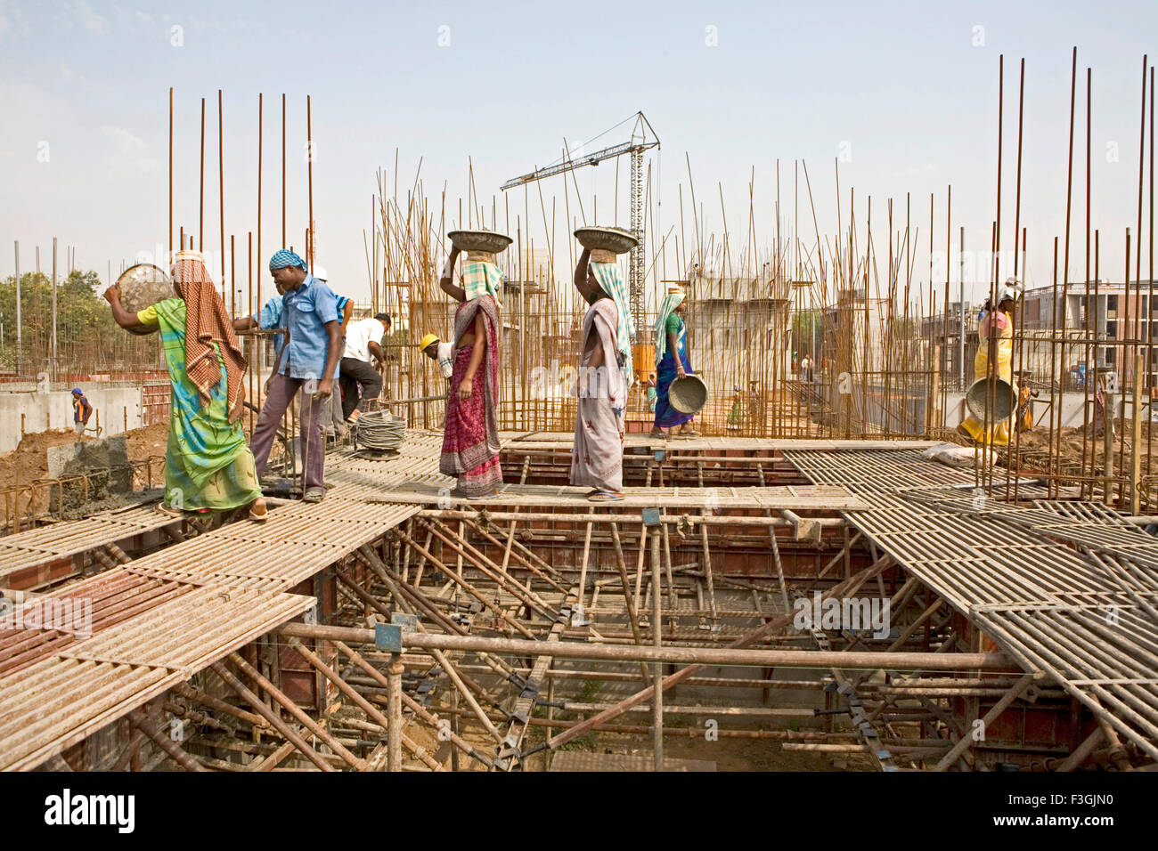 Donne lavoratori edili portando la miscela di calcestruzzo sulla loro testa durante una lastra ripieno Il processo di costruzione Ahmedabad Foto Stock