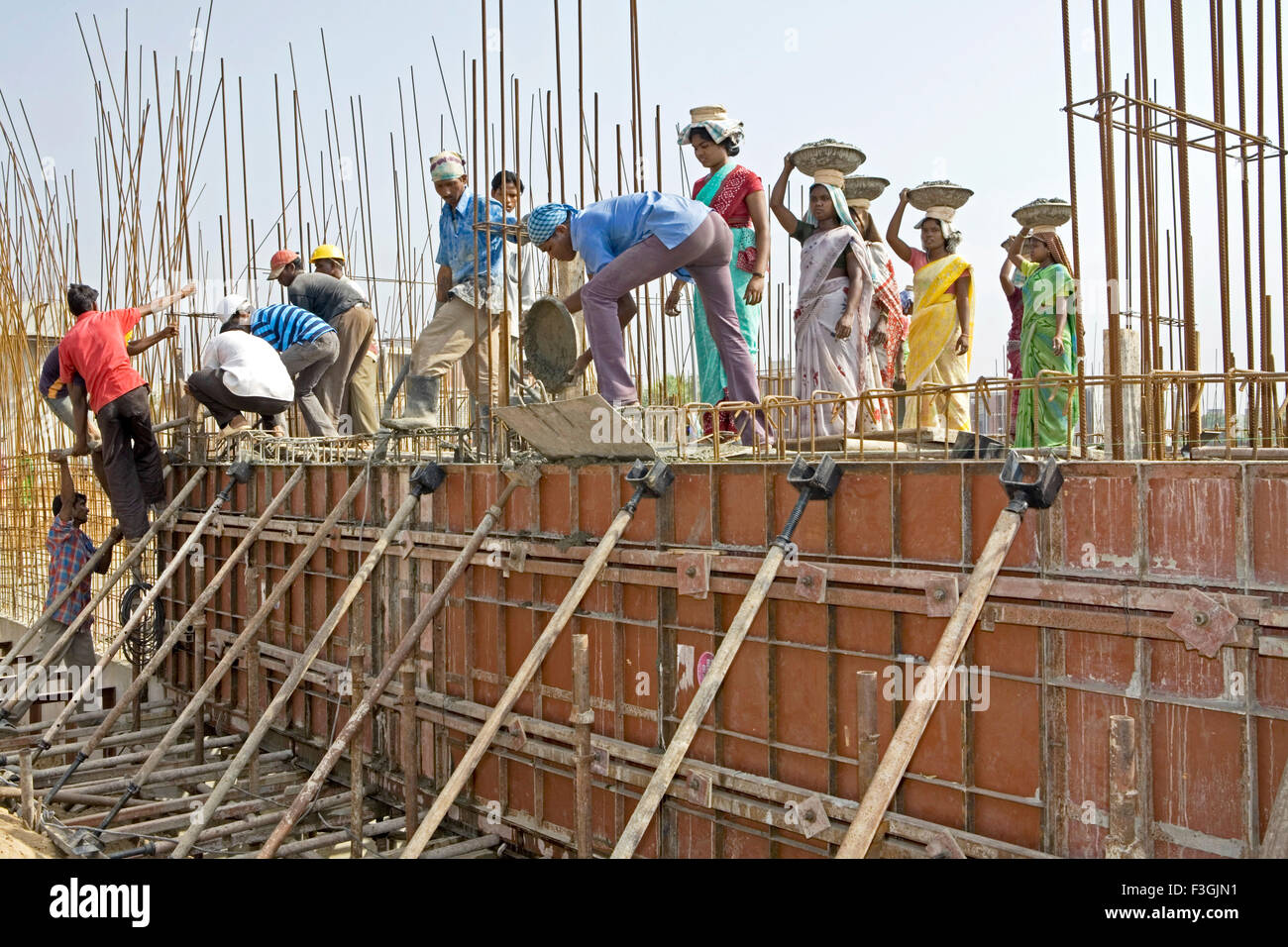 Operai di costruzione impegnati nell'attività di riempimento della lastra concreta in un luogo di costruzione in Ahmedabad ; Gujarat ; India ; operai indiani Foto Stock