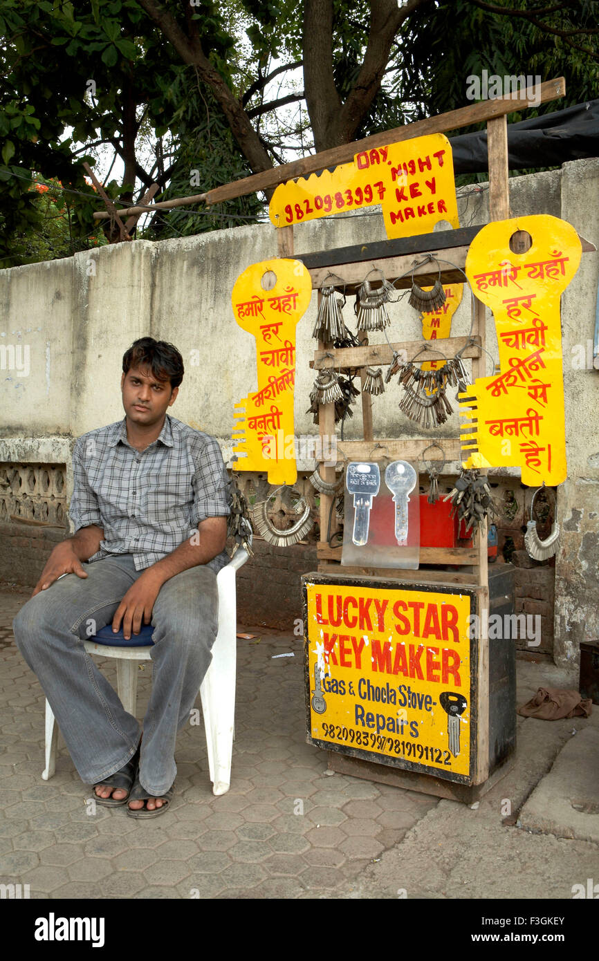 Un duplicato di chiave maker con visualizzazione del tasto enorme ritagli impostazione la sua merce su un sentiero ; Mumbai Bombay Foto Stock
