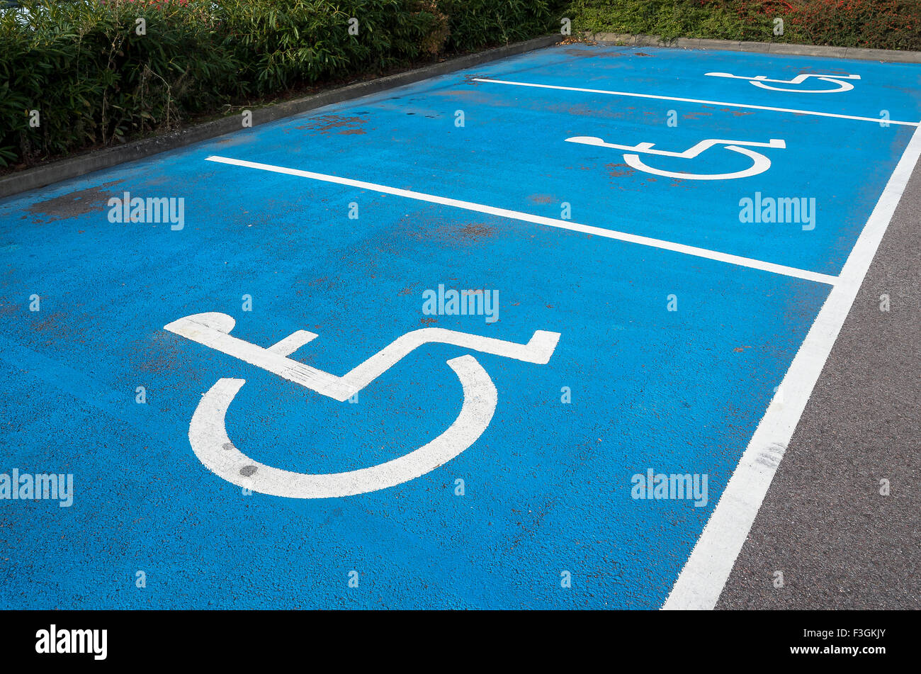 Tre parcheggio disabili alloggiamenti contrassegnati con il simbolo universale e colori nel Regno Unito Foto Stock