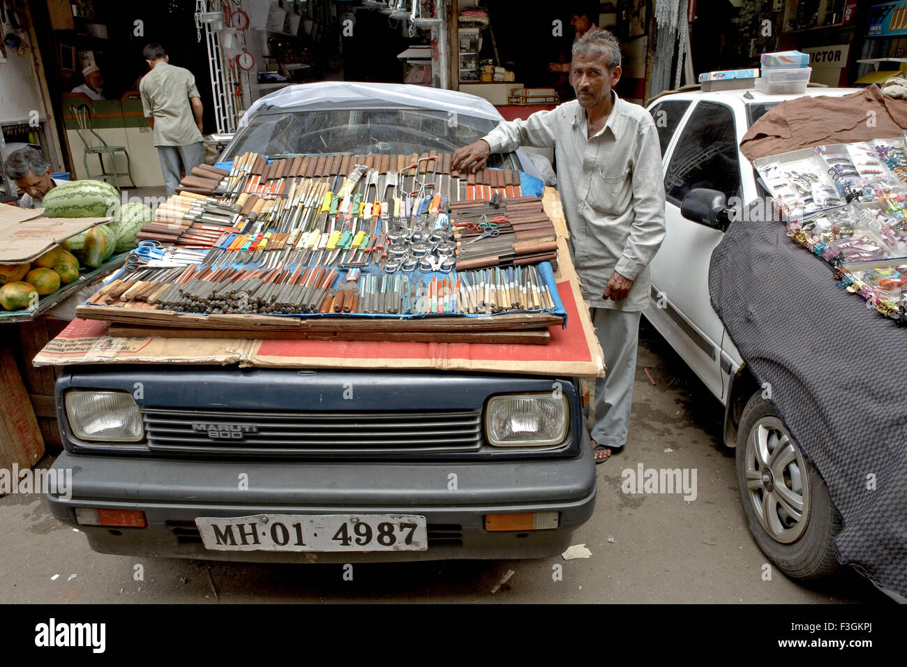 Un hawker trova un modo ingegnoso per visualizzare il suo ware sul cofano del motore di un'auto ; Mumbai Bombay ; Maharashtra ; India Foto Stock