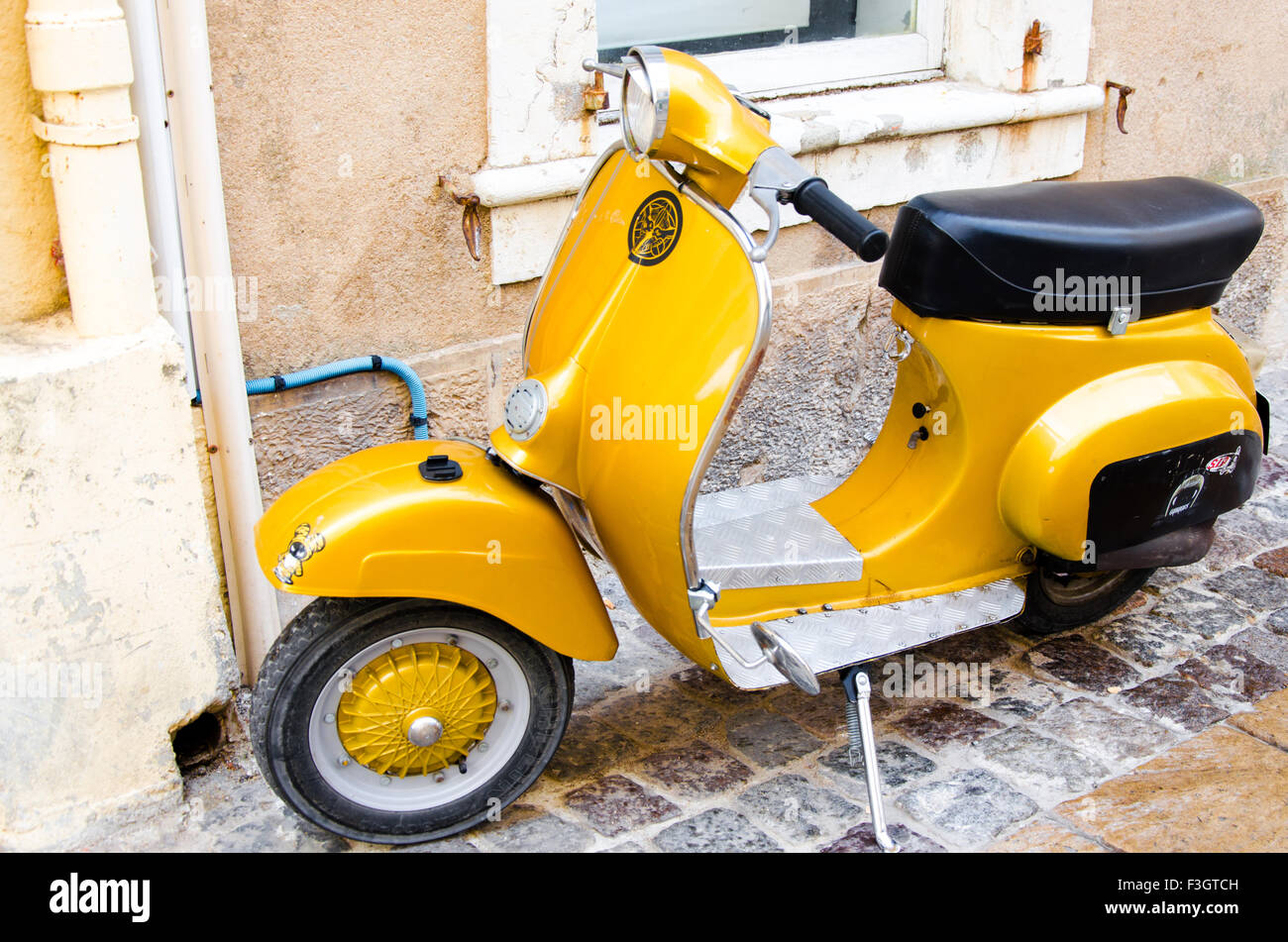 Giallo scooter Vespa parcheggiata in una strada a Saint Tropez Foto Stock