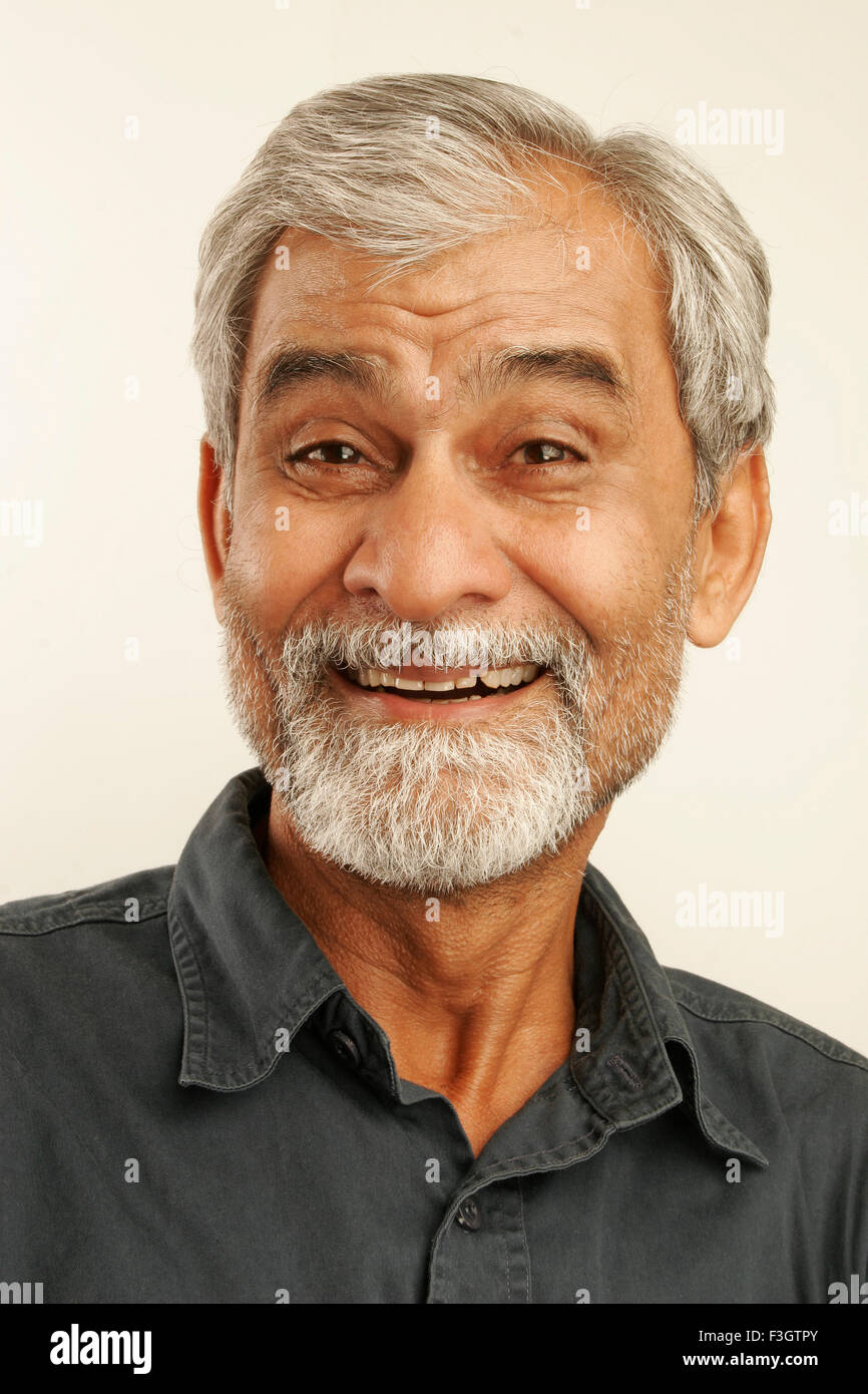 South Asian Indian vecchio uomo tardi anni cinquanta con i capelli grigi e la barba scura che indossa maglietta blu che esprimono con stupore il signor#340 Foto Stock