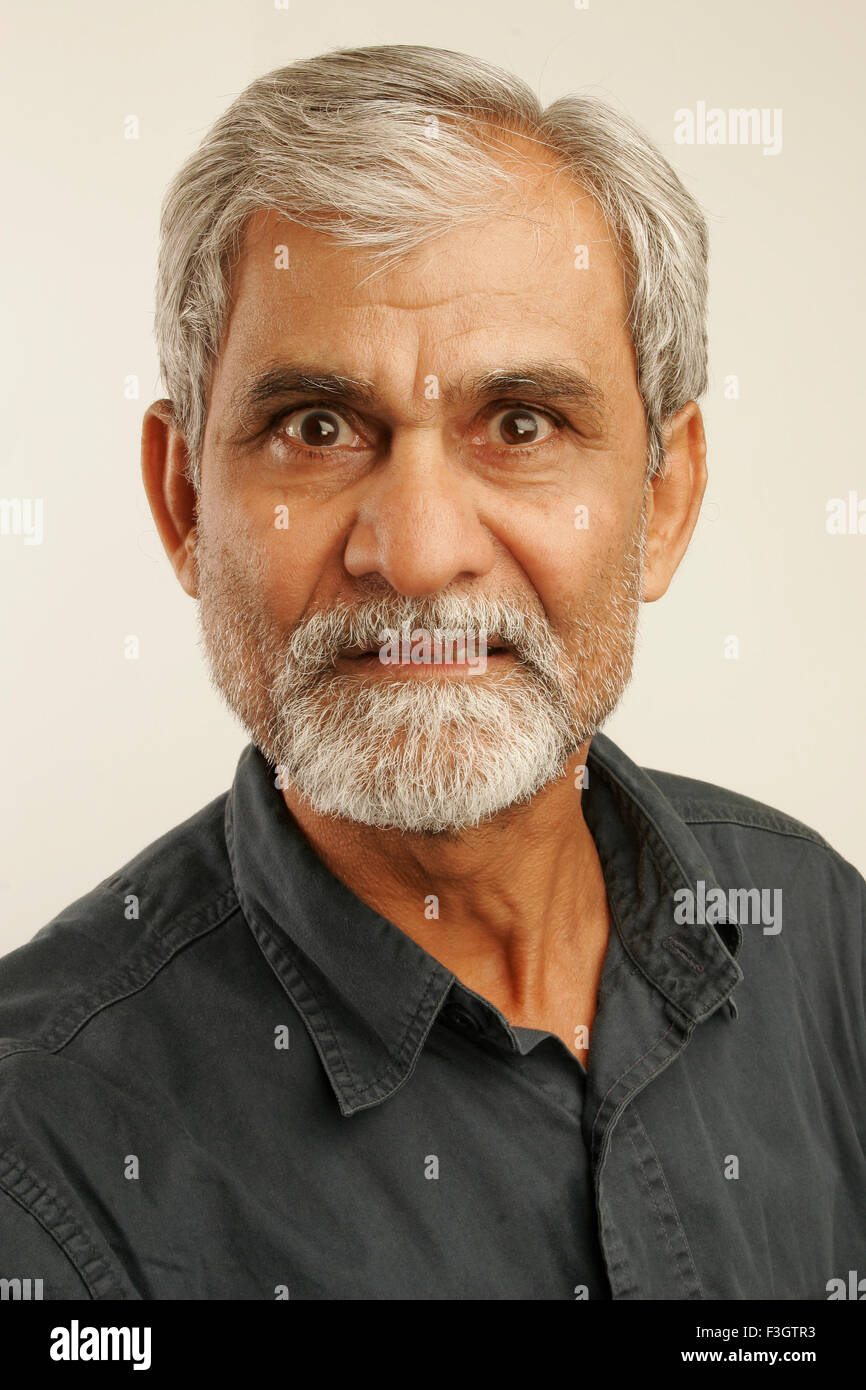 South Asian Indian vecchio uomo tardi anni cinquanta con i capelli grigi e la barba scura che indossa maglietta blu esprimendo rabbia signor#340 Foto Stock