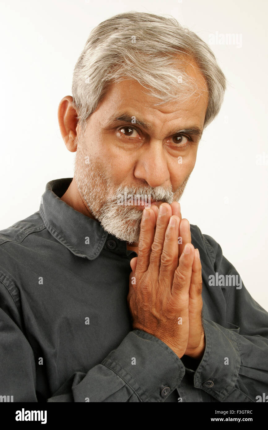 South Asian Indian vecchio uomo tardi anni cinquanta con i capelli grigi e la barba scura che indossa maglietta blu rilassante ma seriamente pensando Foto Stock