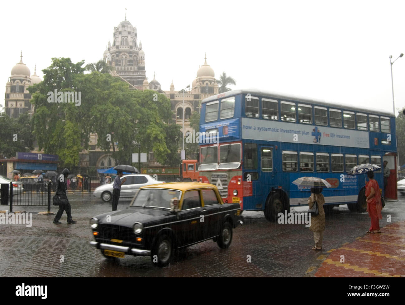 Heavy Rain e Churchgate Station building persone con ombrellone e trasporto in monsone ; Mumbai Bombay ; Maharashtra ; India Foto Stock