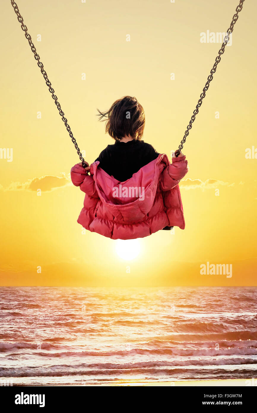 Bambina sull'altalena guardando il tramonto sul mare Foto stock - Alamy