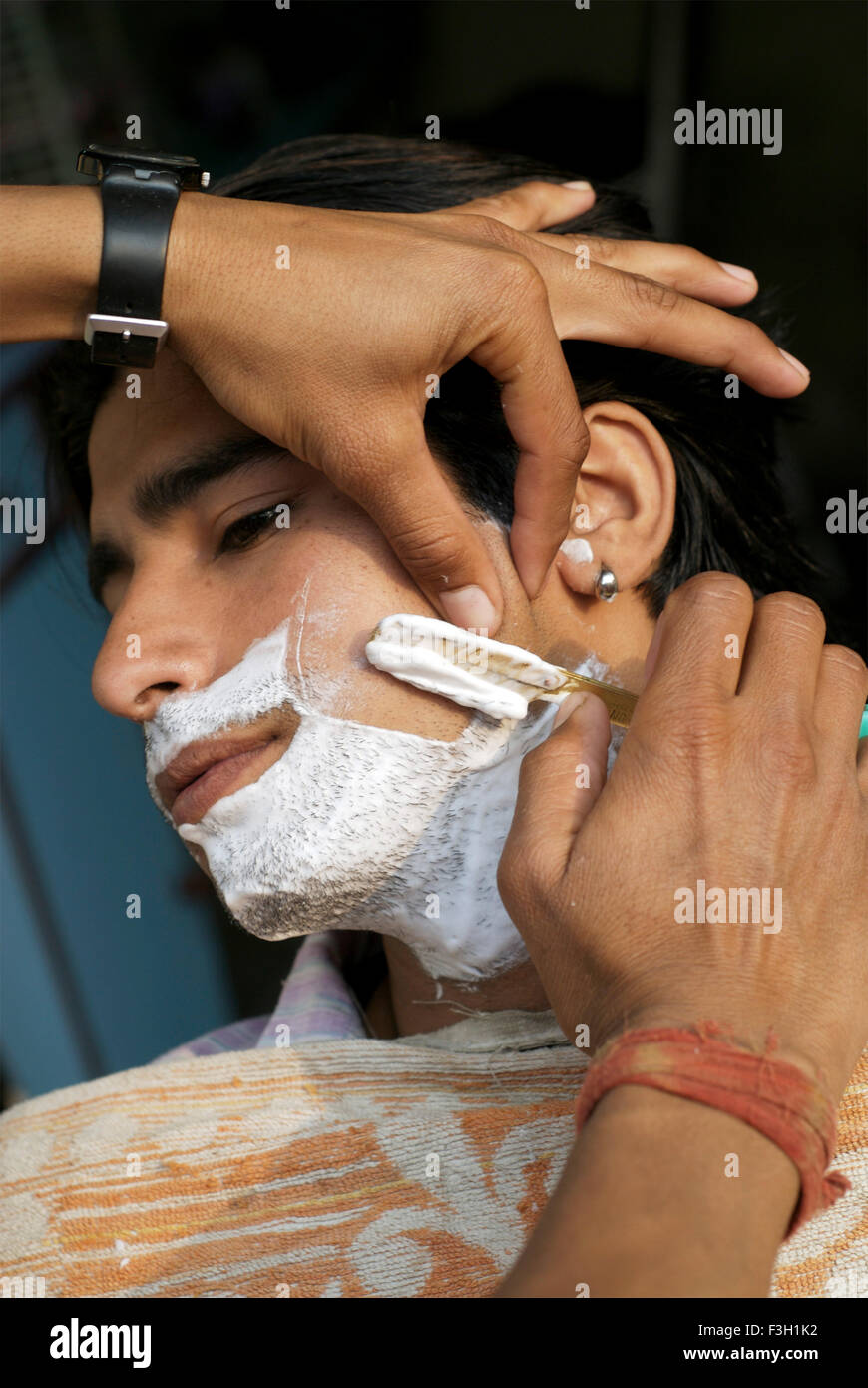 Un giovane uomo di ottenere la sua barba rasata al Taj capelli e salone di bellezza ; Dehradun ; Uttaranchal ; India Foto Stock