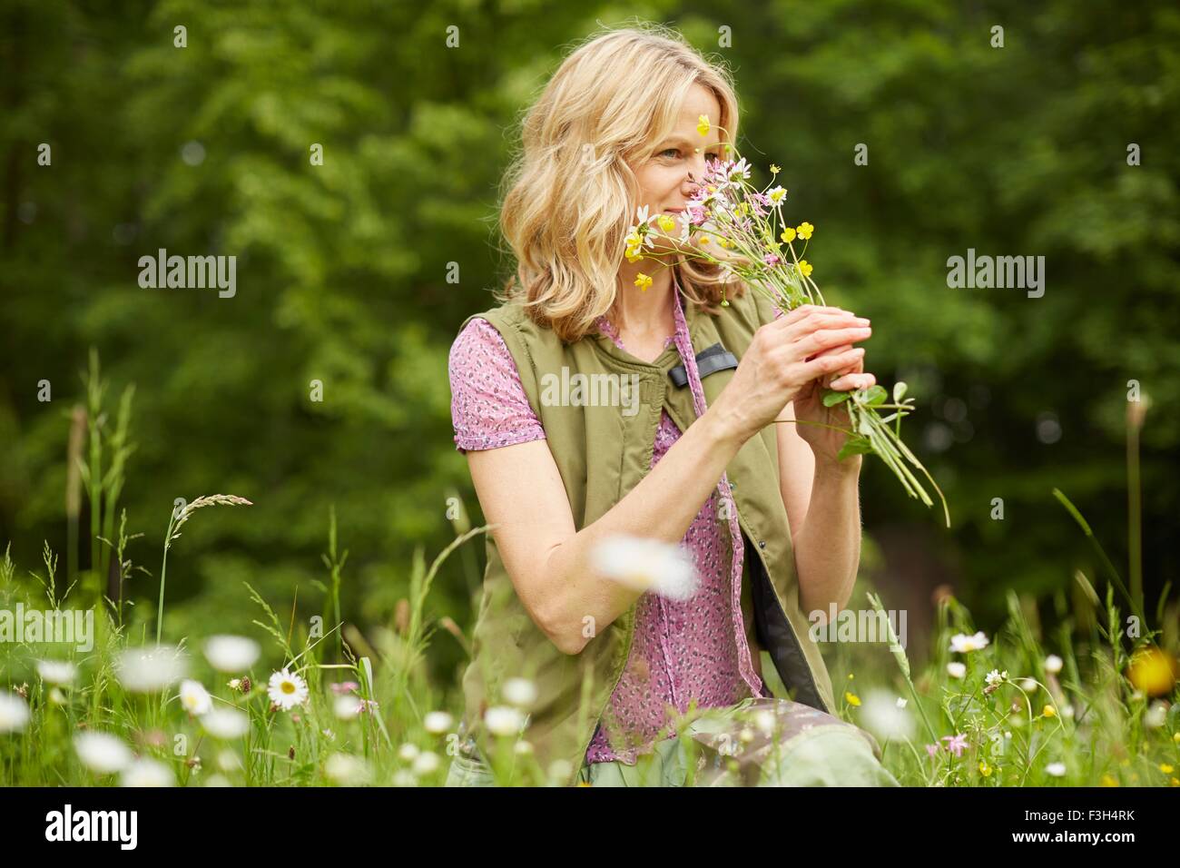 Donna matura in giardino, profumati fiori Foto Stock